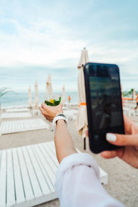 holding a phone and taking a picture of a cocktail