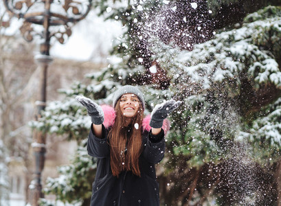 The girl throws snow up in the city