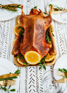 Festive table setting with whole roasted goose on a golden tray for celebrate event  Thanksgiving or Christmas family dinner
