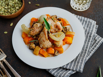 Seasonal autumn low calorie recipe from baked turkey medallions with pumpkin  onion  champignons and sage on a white plate