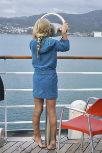 Curious girl on cruise ship looking through viewfinder at ocean 01