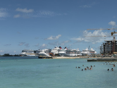 Tourists swimming in sunny ocean with cruise ships in background 01