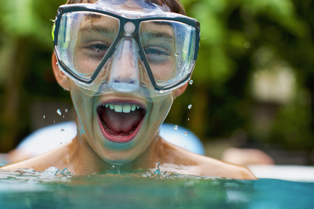 Portrait exuberant boy in swimming goggles swimming 01