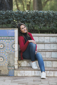 Portrait happy woman sitting on park steps next to mosaic wall 01