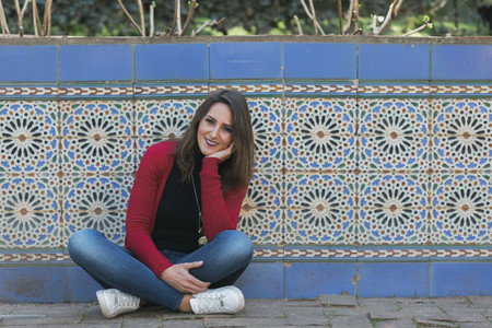 Portrait smiling woman sitting along mosaic wall 01