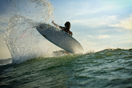 Surfer catching air behind wave on ocean 01