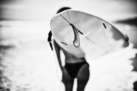 Female surfer carrying surfboard on ocean beach 01