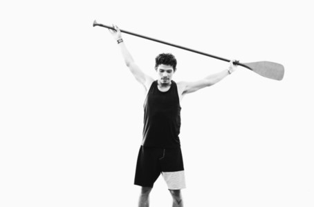 Young fit man holding oar overhead 01