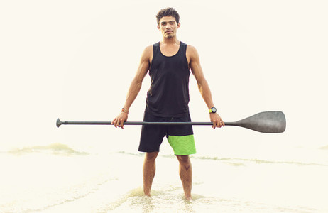 Portrait confident young man holding oar in ocean surf 01