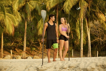 Young couple with oars on sunny  tropical beach 01