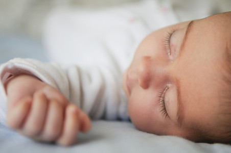 Newborn baby girl sleeping on blue sheets