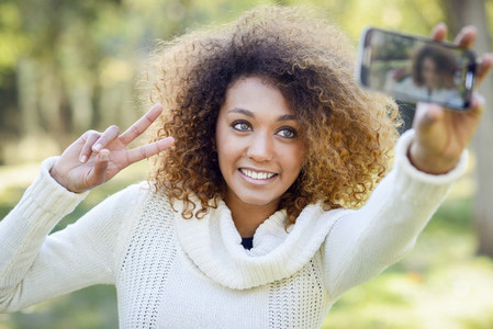 Young African American girl selfie in the park with a smartphone