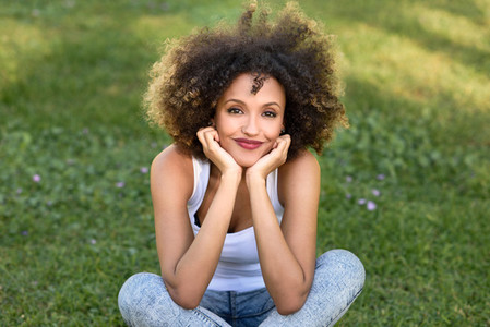 Young black woman with afro hairstyle sitting in urban park