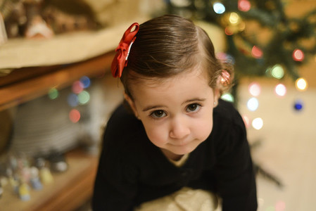 Little girl at home with decoration and defocused Christmas ligh