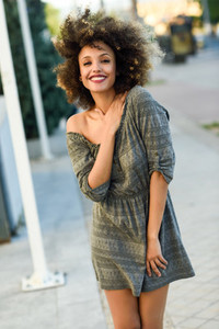 Young black woman with afro hairstyle smiling in urban backgroun