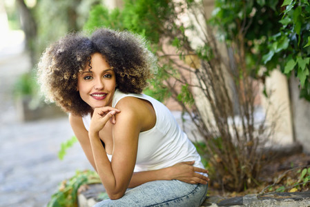 Young black woman with afro hairstyle smiling in urban park