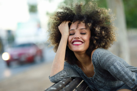 Young black woman with afro hairstyle smiling in urban backgroun