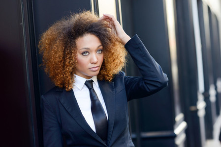 Black businesswoman wearing suit and tie in urban background