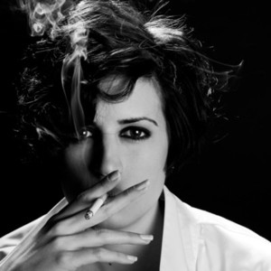 Elegant brunette woman smoking a cigarette on black background