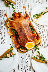 Festive table setting with whole roasted goose on a golden tray for celebrate event or Christmas family dinner