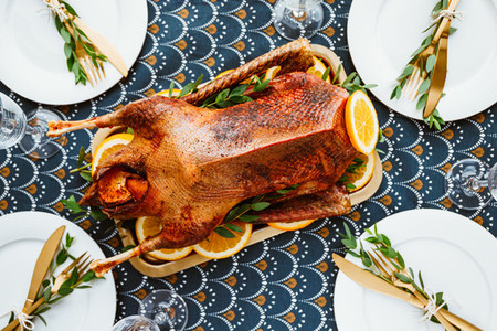 Festive table setting with whole roasted goose on a golden tray for celebrate event or Christmas family dinner Top view flat lay