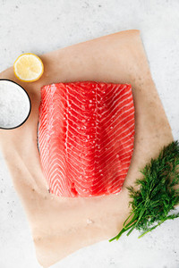 Top view of fresh raw salmon fillet with dill  sea salt and lemon on a table for cooking  Recipe for ketogenic or paleo diet
