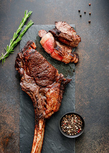 Top view of grilled beef steak Tomahawk with spices on a black slate  Flat lay  dinner concept