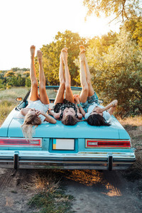 Three girls are lying on the trunk