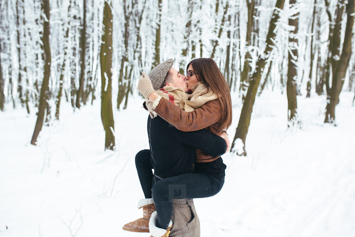 guy holds the girl on hands in snow park