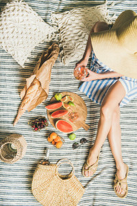 Picnic concept with woman in dress  wine  fruits and baguette