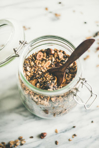 Buckwheat and chocolate granola with hazelnuts in glass jar close up