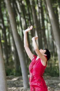 Woman dressed in red  meditating in the forest