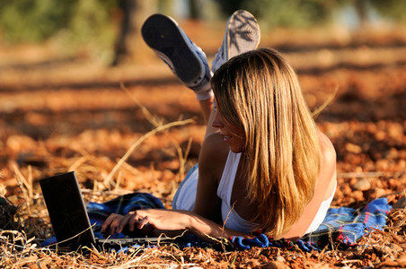 Girl with a laptop in a field in autumn