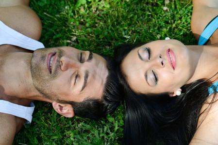 Happy smiling couple laying on green grass