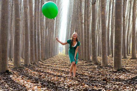 Beautiful blonde girl dressed in green laughing in the forest