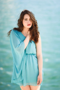 Woman with blue eyes wearing blue dress in the beach