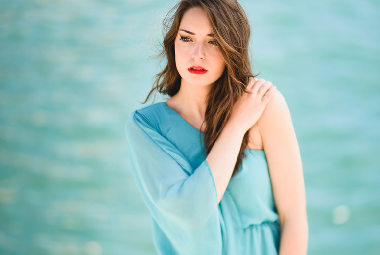 Woman with blue eyes wearing blue dress in the beach.