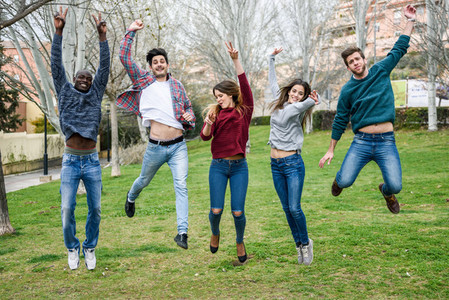 Group of young people jumping together outdoors
