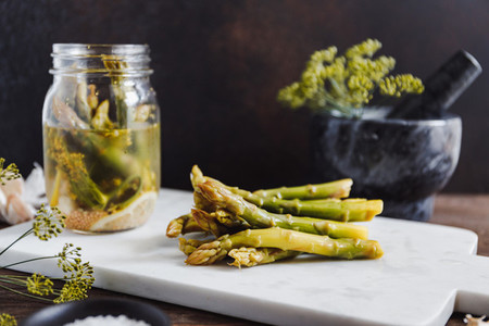 Pickled asparagus on a white marble tray  Seasonal canning vegetable recipe