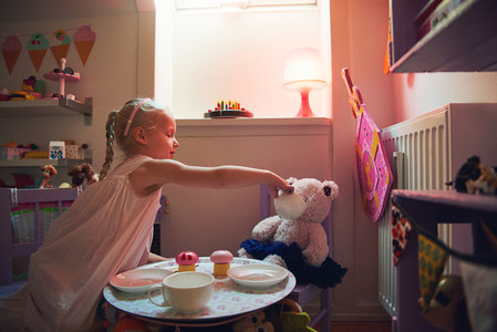 Girl playing tea party with her toy bear