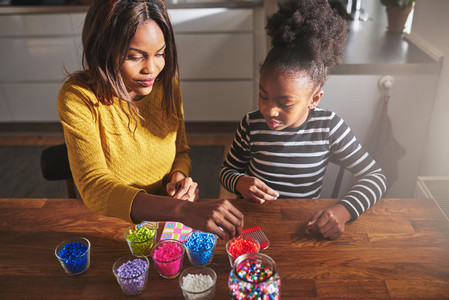 Adult female choosing beads with child at table