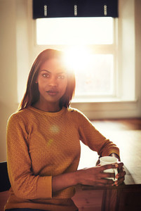 Serious black woman at table in front of window