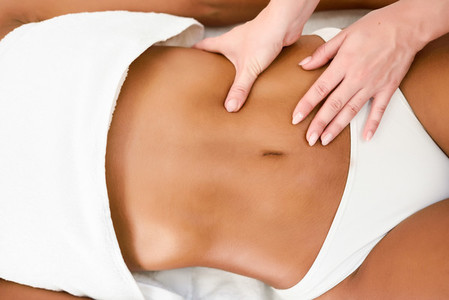 Woman receiving abdomen massage in spa wellness center