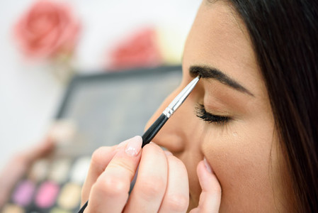 Makeup artist putting make up on an womans eyebrows