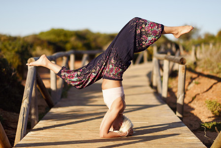 Caucasian female practicing yoga on wooden bridge