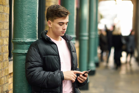 Young urban man using smartphone in urban background