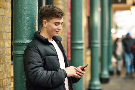 Young urban man using smartphone in urban background