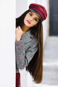 Beautiful girl with very long hair wearing winter coat and cap outdoors
