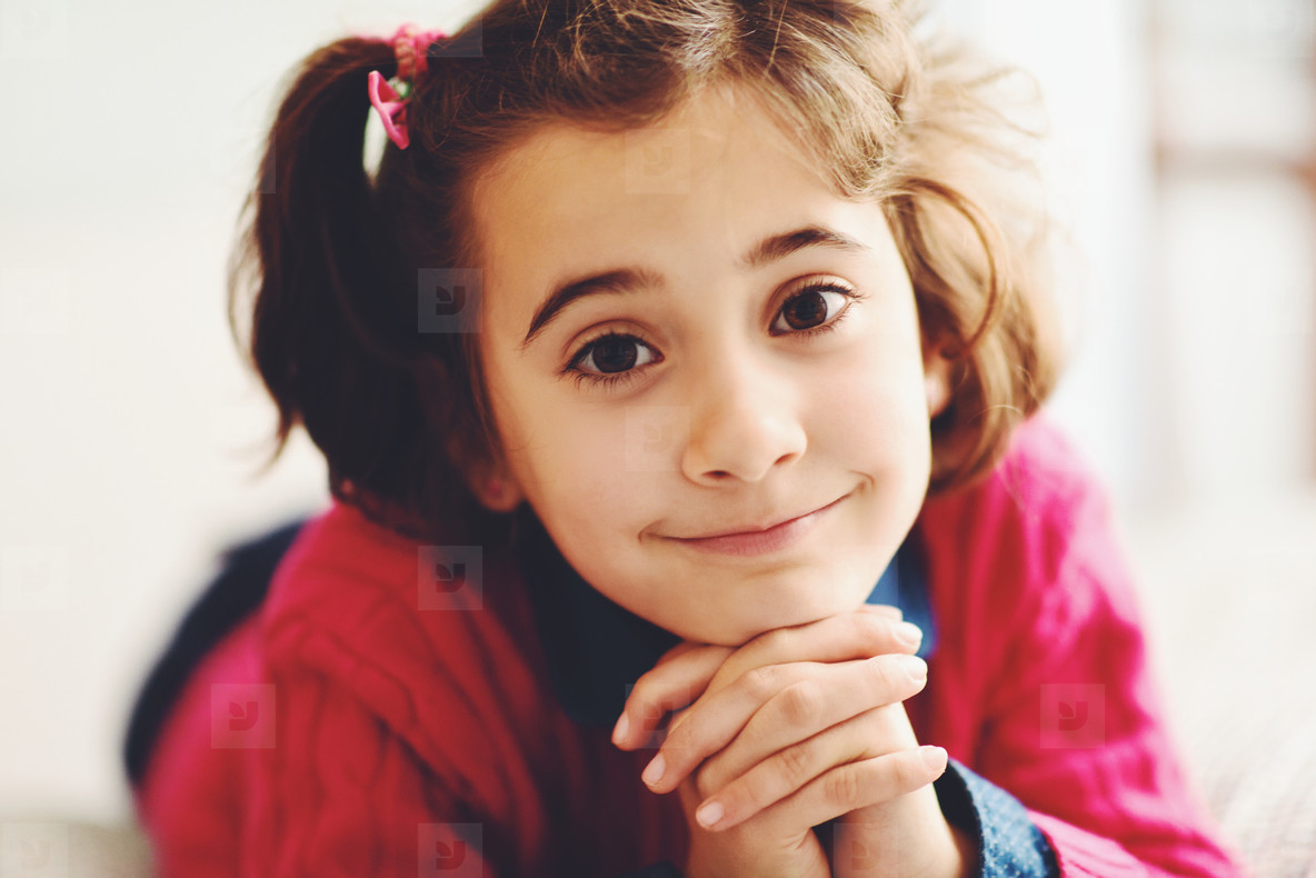 Adorable little girl with sweet smile lying down on bed