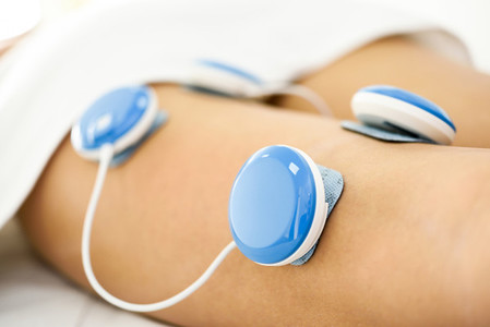 Electro stimulation in physical therapy to a young woman leg